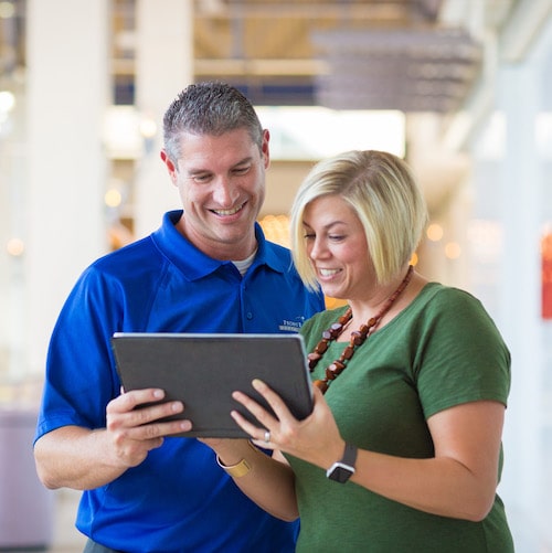 Man and a woman looking at a tablet while smiling