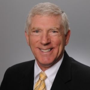 Dr. Wayne Kerr in black suit with yellow tie