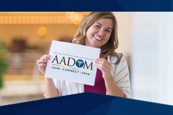 A dental manager holding up the AADOM logo